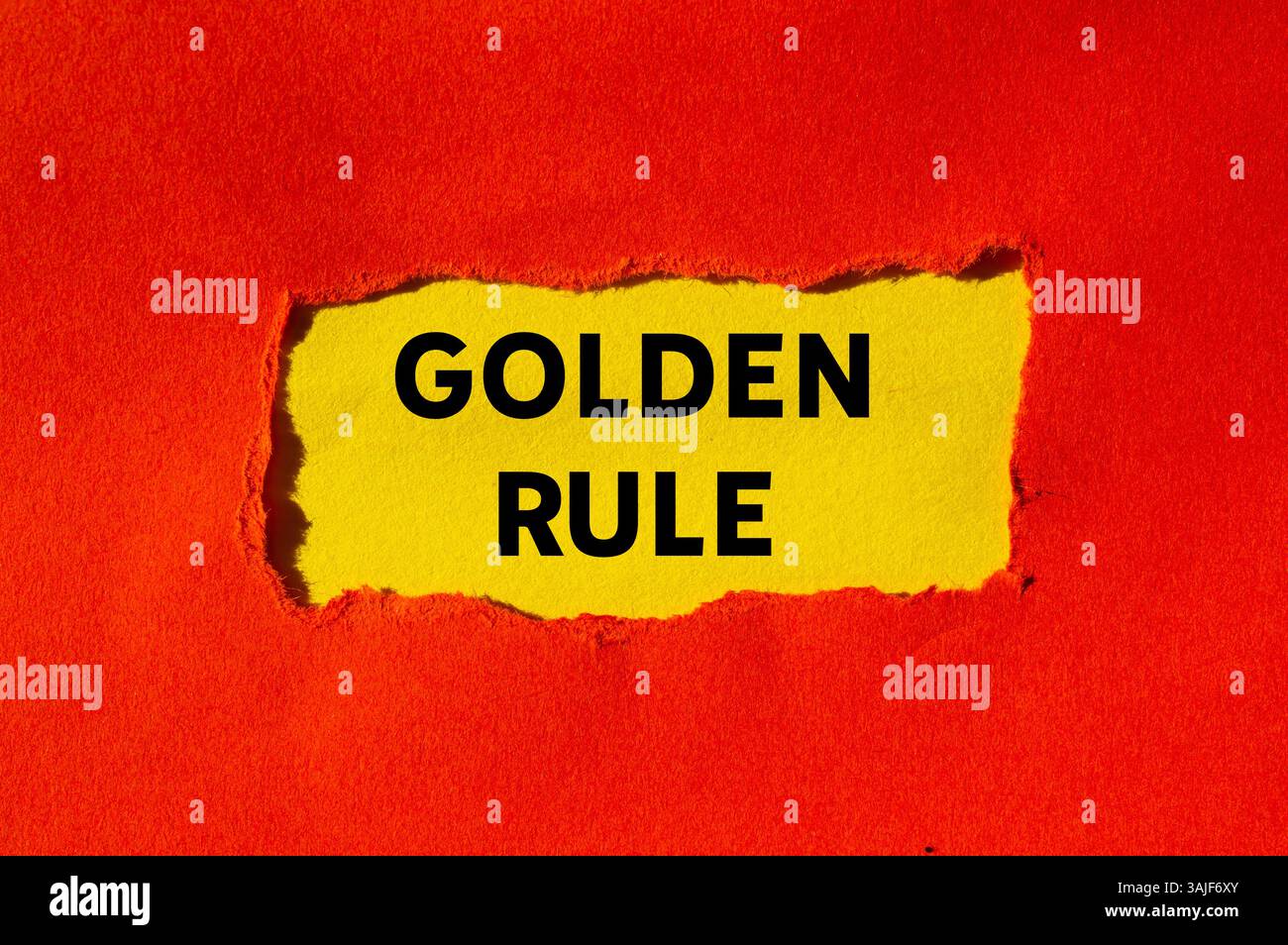 Goldene Regelnachricht auf gerissenem rotem Papier auf gelbem Hintergrund. Konzeptionelles goldenes Regelsymbol. Kopierbereich. Stockfoto