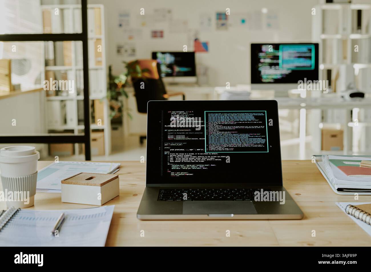 Mittlere Nahaufnahme des Laptops mit Codes auf dem Bildschirm auf dem Holztisch im Büro Stockfoto