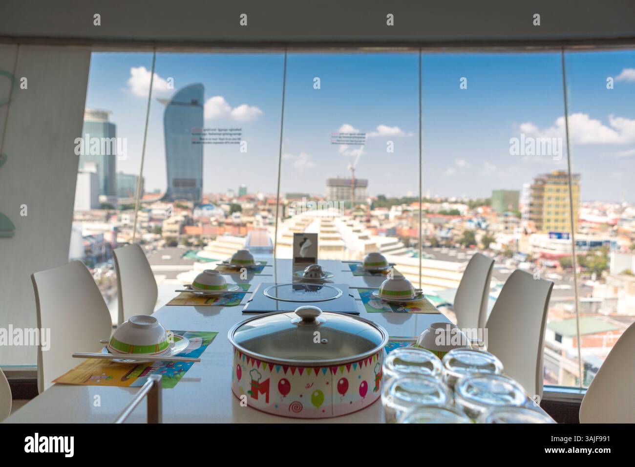 Hot-Pot-Tisch mit Blick auf die Stadt durch ein großes Fenster. Stockfoto