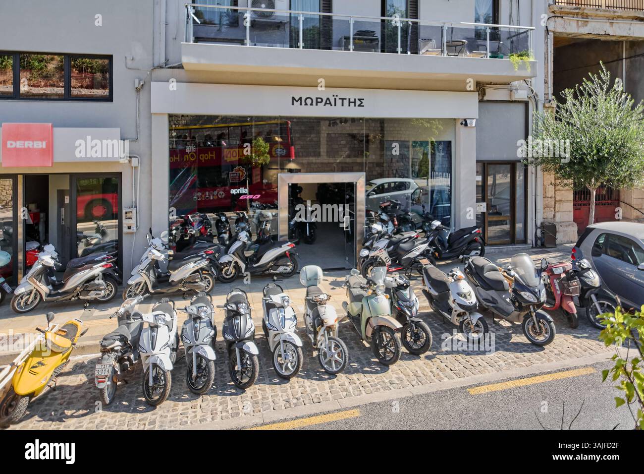 Kreta. Griechenland - 11. april 2025: Ein Motorradhändler auf Kreta mit griechischen Schildern und mehreren Motorrädern im Außenbereich. Die städtische Umgebung und Stockfoto