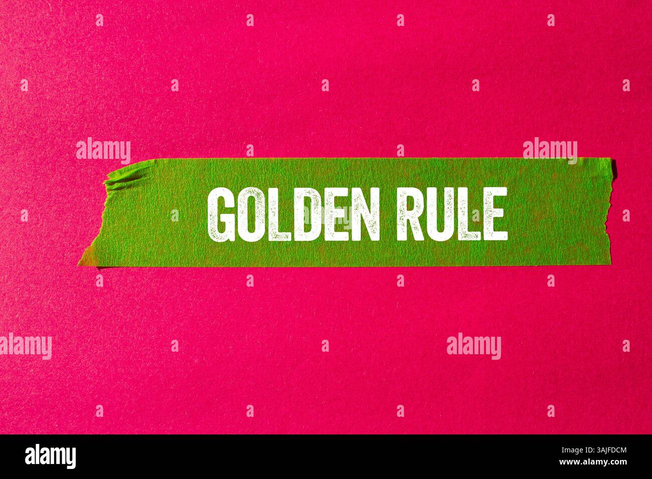Goldene Regel-Nachricht auf gerissenem, gerissenem grünen Papierband auf rosa Hintergrund. Konzeptionelles goldenes Regelsymbol. Kopierbereich. Stockfoto