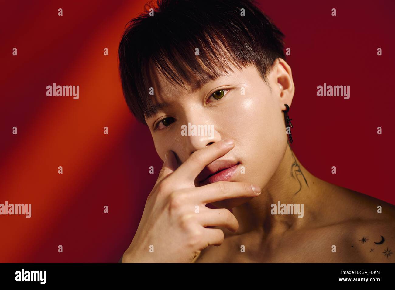 Ein selbstbewusster junger asiatischer Mann zeigt seinen einzigartigen Stil und Charme in einer lebendigen Umgebung. Stockfoto