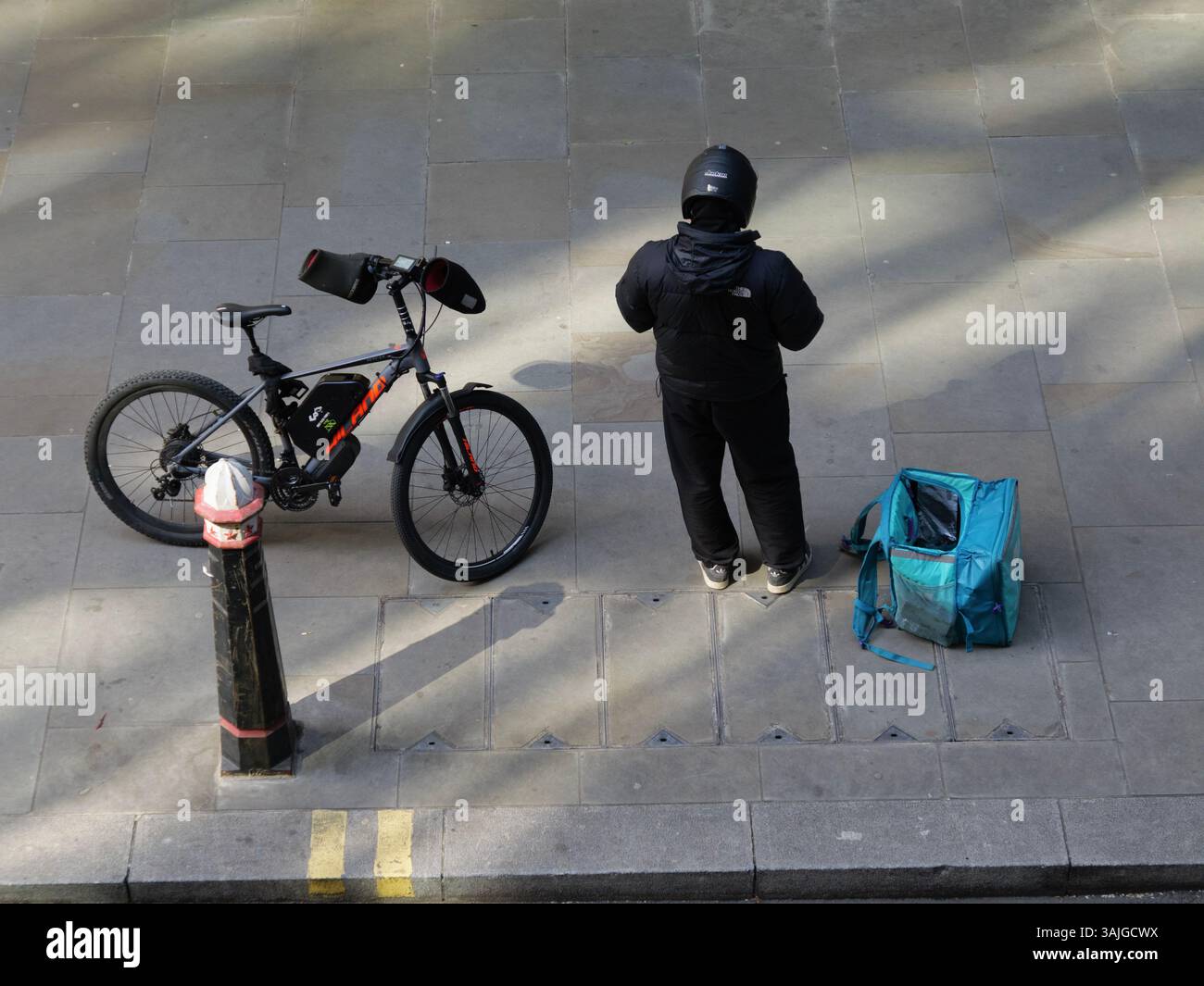 Deliveroo Fahrradfahrer, der vor Bürogebäuden steht, Moorgate, City of London, Großbritannien, mit einer Tasche mit Lebensmitteln Stockfoto