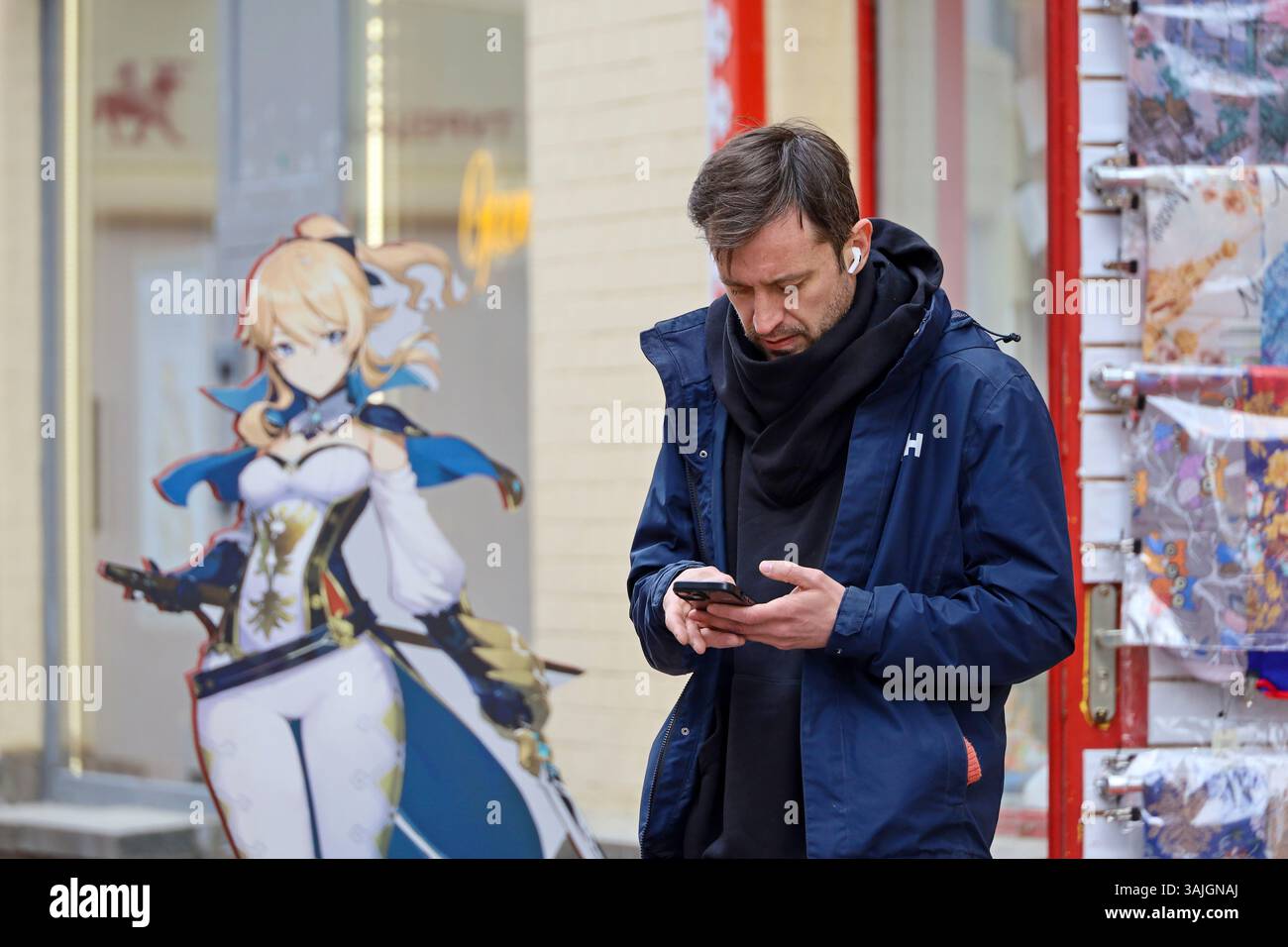 Mann, der ein Smartphone auf der Straße benutzt und in der Nähe der Anime steht Stockfoto