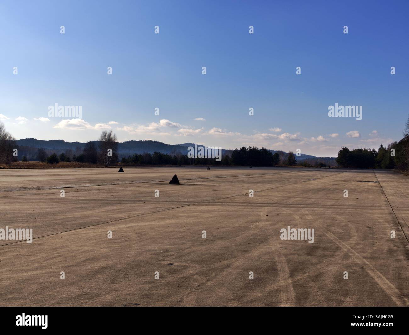Eine alte Start- und Landebahn des Flughafens mit umliegenden Wäldern. Es gibt Dreiecke auf der Landebahn als Barrieren. Stockfoto
