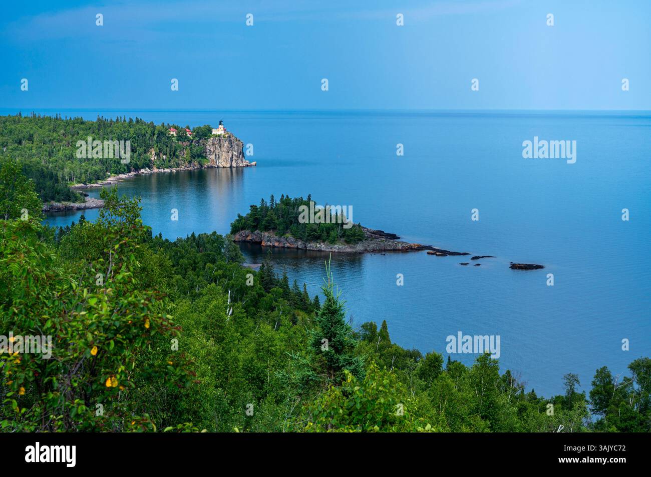Malerischer Leuchtturm mit Blick auf eine felsige Küste im unberührten blauen Wasser Stockfoto