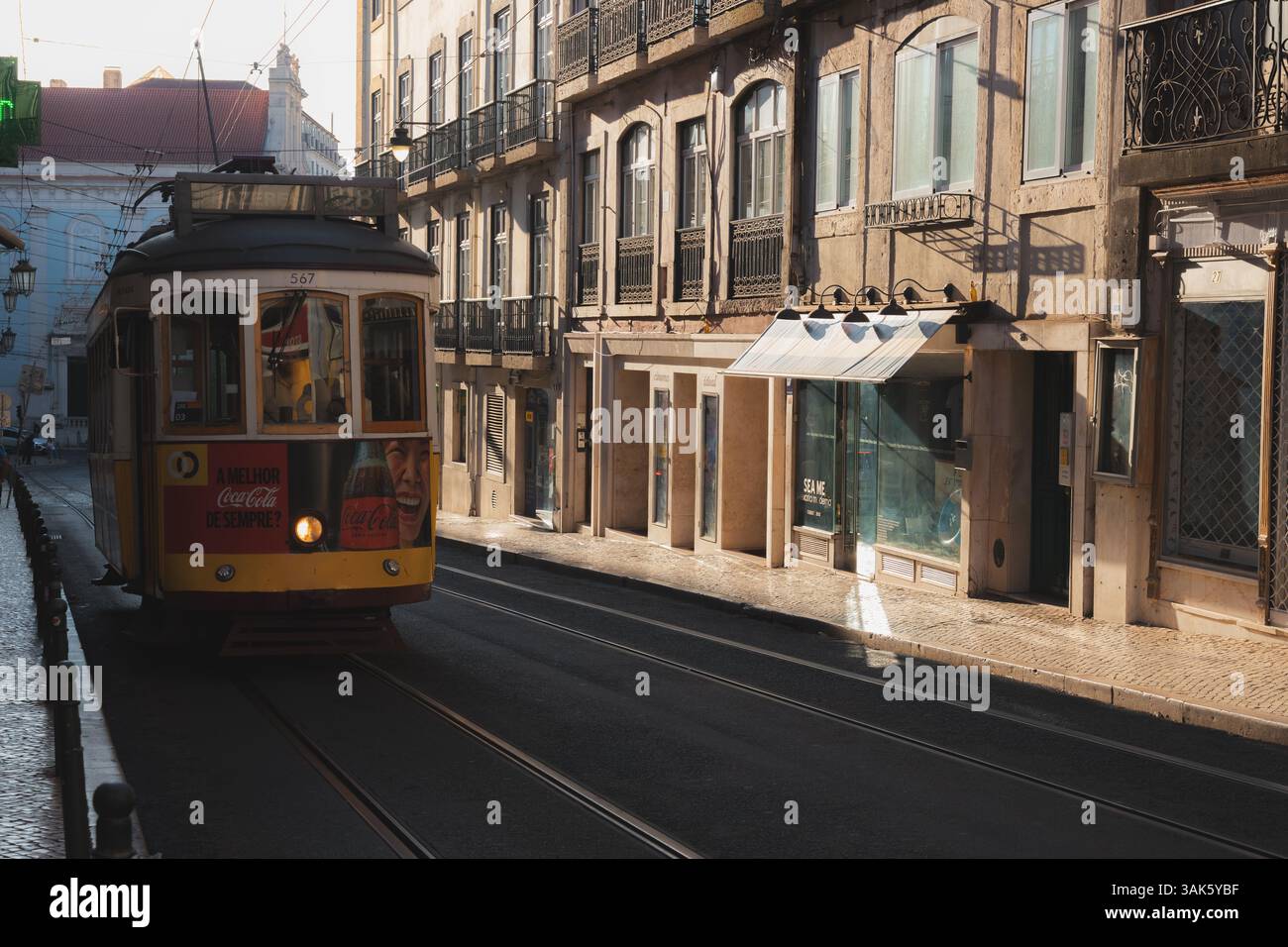 Lissabon, Portugal - 15. Juli 2024: Straßenbahn 28 fährt während der goldenen Stunde durch eine historische Straße in Bairro Alto, Lissabon Stockfoto