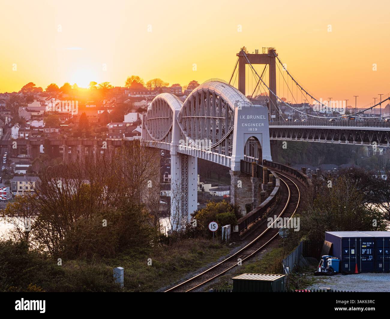 1859 Royal Albert Eisenbahnbrücke über den Tamar bei Sonnenuntergang. Saltash und Tamar Road Bridge im Hintergrund. Stockfoto