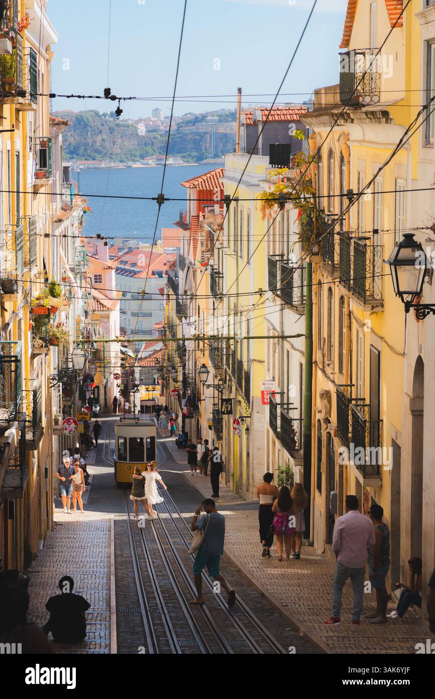 Lissabon, Portual - 14. Juli 2024: Mit der Bica-Seilbahn auf einer schmalen Kopfsteinpflasterstraße in Lissabon, mit historischen Gebäuden und geschäftigen Touristen, an Stockfoto