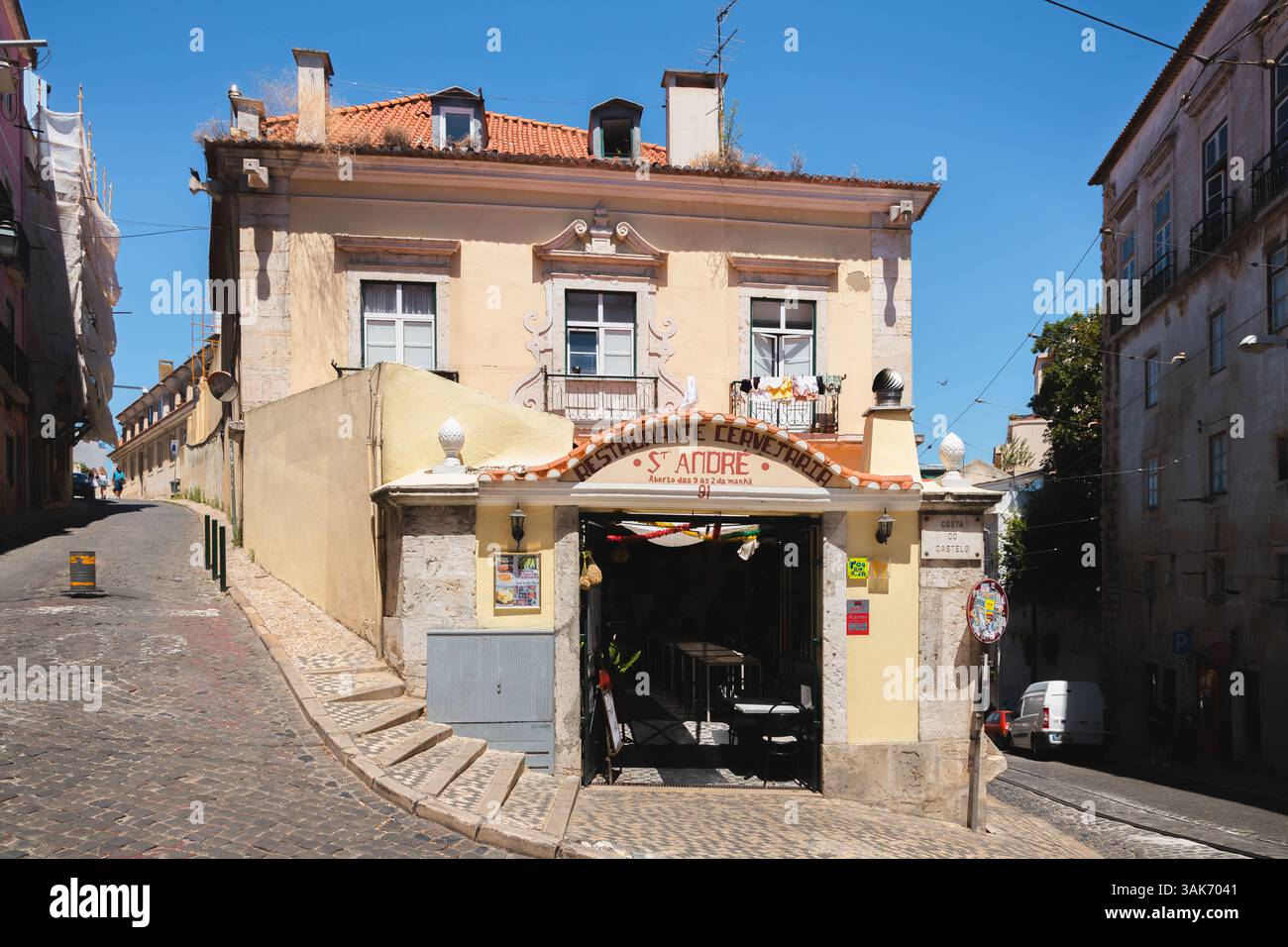 Lissabon, Portugal - 12. Juli 2024: Ein traditionelles Restaurant im Lissabonner Stadtteil Alfama befindet sich auf einer Kopfsteinpflasterstraße mit Straßenbahnschienen und einer bezaubernden Atmosphäre Stockfoto