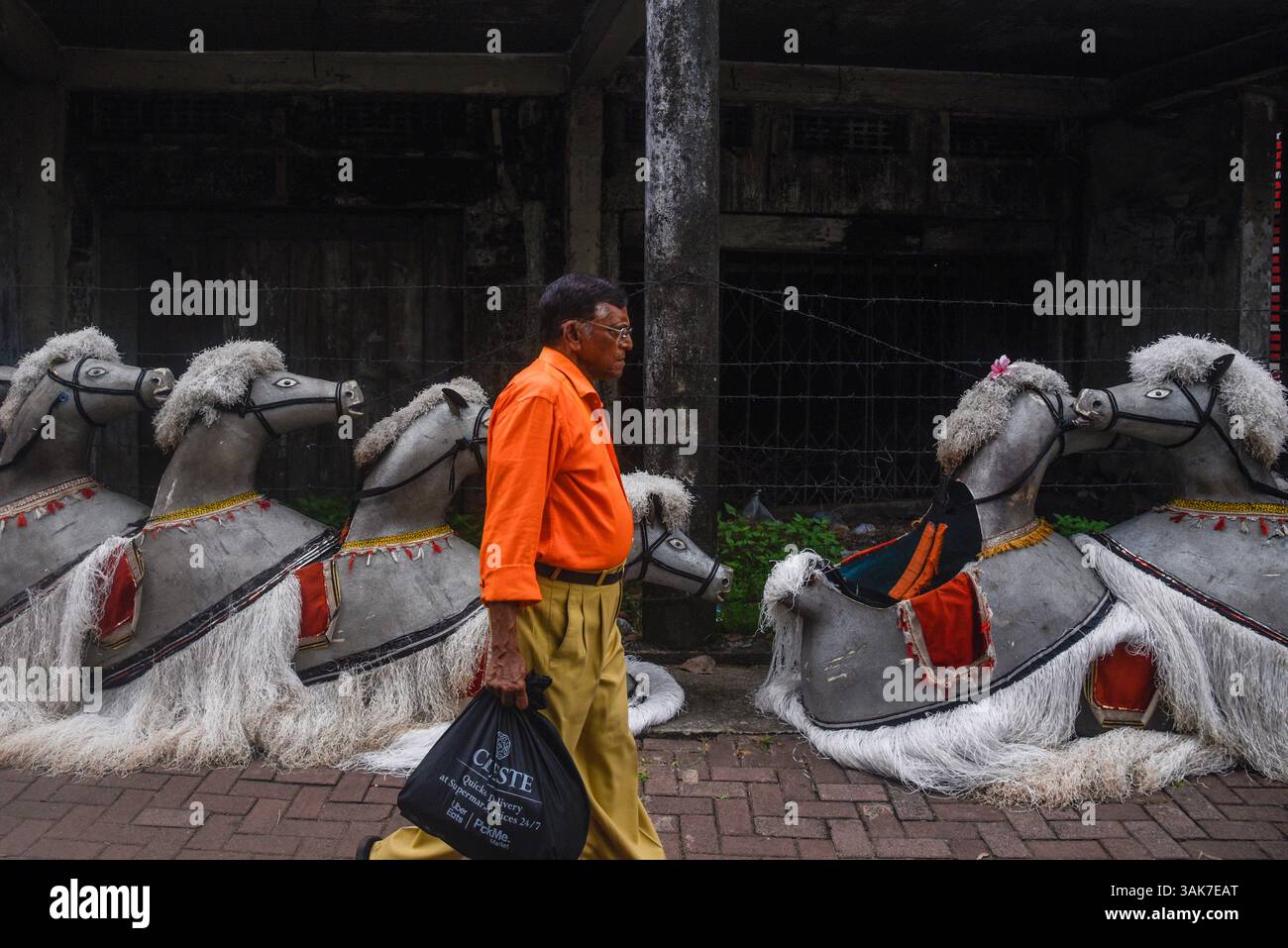 Das Chariot Festival im Sri Muttumariamman Hindu Temple in Sri Lanka Ein Mann spaziert am 11. April 2025 an Requisiten vorbei, die vor dem Chariot Festival im Sri Muttumariamman Hindu Temple in Moratuwa, Sri Lanka stattfinden. Das Festival ist ein lebendiges religiöses Ereignis, das einheimische Anhänger und Besucher gleichermaßen anzieht. Das Festival wird jährlich veranstaltet und ehrt die hinduistische Göttin Mariamman, die für ihre Schutzkräfte und Heilkräfte verehrt wird. Im Mittelpunkt der Feier steht die zeremonielle Prozession eines reich geschmückten Wagens, der die Gottheiten-Statue durch die Straßen trägt, begleitet von traditioneller Musik, Trommeln und Darbietungen. T Stockfoto Das Chariot Festival im Sri Muttumariamman Hindu Temple in Sri Lanka Ein Mann spaziert am 11. April 2025 an Requisiten vorbei, die vor dem Chariot Festival im Sri Muttumariamman Hindu Temple in Moratuwa, Sri Lanka stattfinden. Das Festival ist ein lebendiges religiöses Ereignis, das einheimische Anhänger und Besucher gleichermaßen anzieht. Das Festival wird jährlich veranstaltet und ehrt die hinduistische Göttin Mariamman, die für ihre Schutzkräfte und Heilkräfte verehrt wird. Im Mittelpunkt der Feier steht die zeremonielle Prozession eines reich geschmückten Wagens, der die Gottheiten-Statue durch die Straßen trägt, begleitet von traditioneller Musik, Trommeln und Darbietungen. T Stockfoto