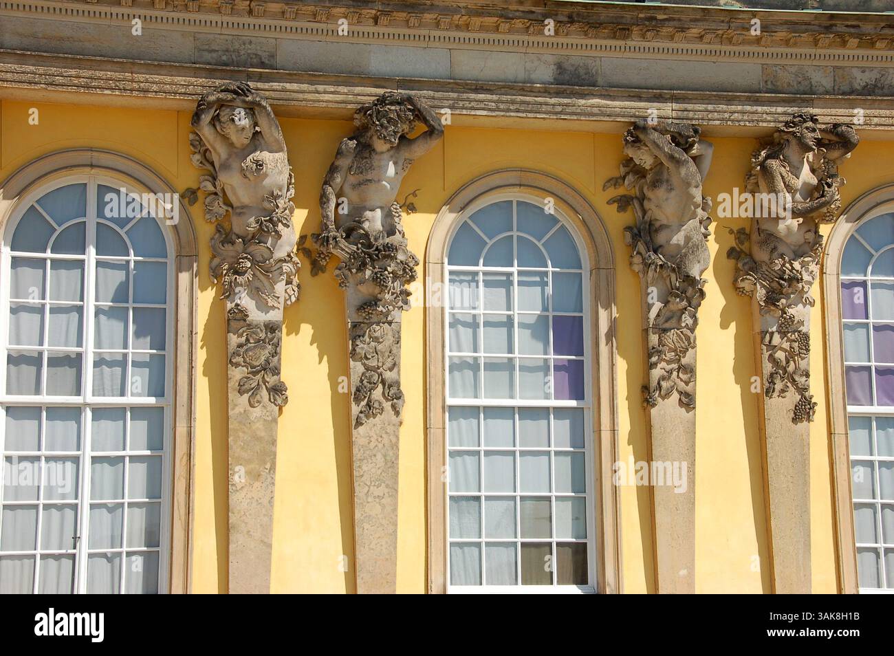 Schloss Sanssouci in Potsdam, Deutschland, mit hellgelber Fassade und kunstvollen Skulpturen unter tiefblauem Himmel Stockfoto