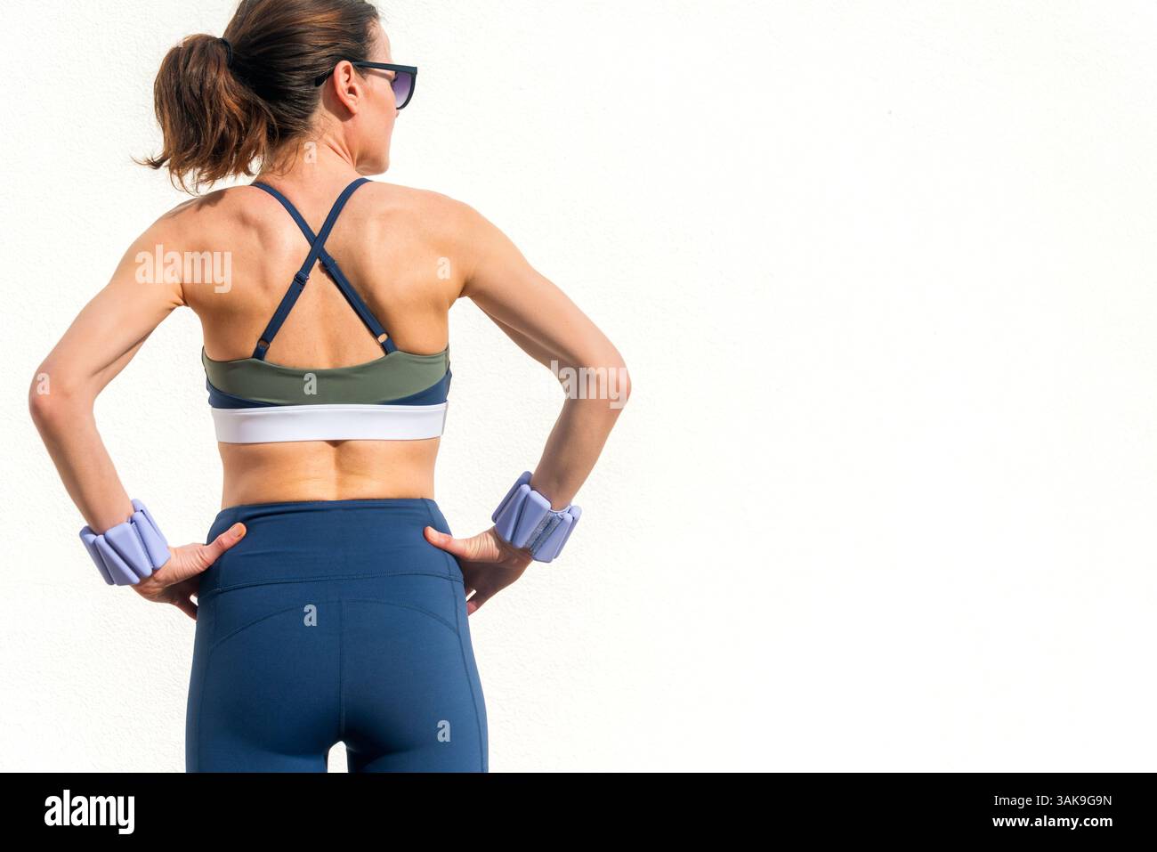Rückansicht einer sportlichen Frau mit verstellbaren Handgelenkgewichten Stockfoto