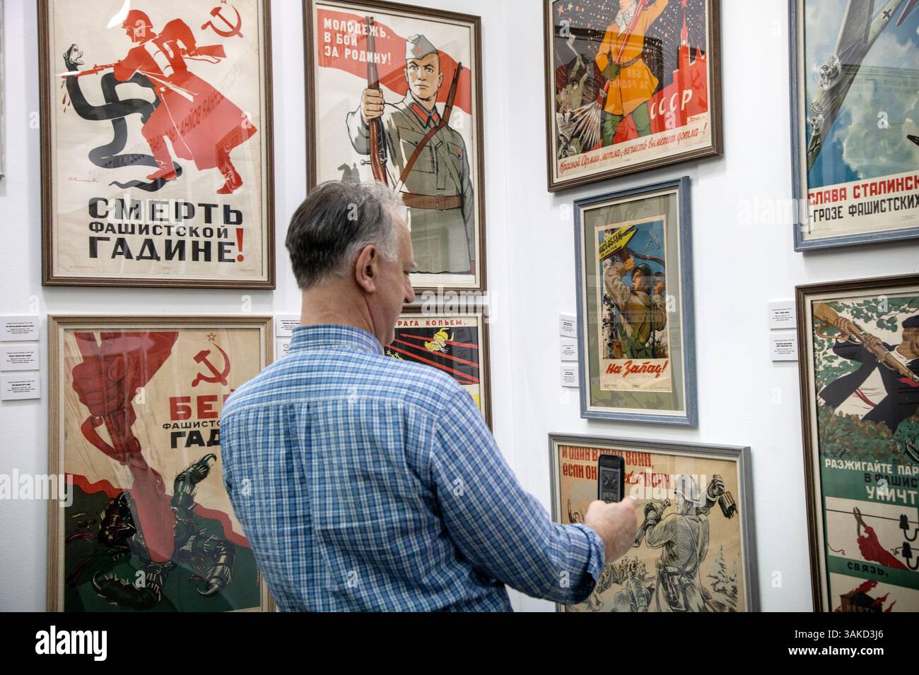 Moskau, Russland. April 2025. Ein Mann fotografiert eine Ausstellung sowjetischer Plakate aus dem Großen Vaterländischen Krieg von 1941-1945 auf der internationalen Buchmesse Non/Fiction Vesna (Frühling) für hochwertige Fiktion und Sachbücher im Messezentrum Gostiny Dvor in Moskau, Russland Stockfoto