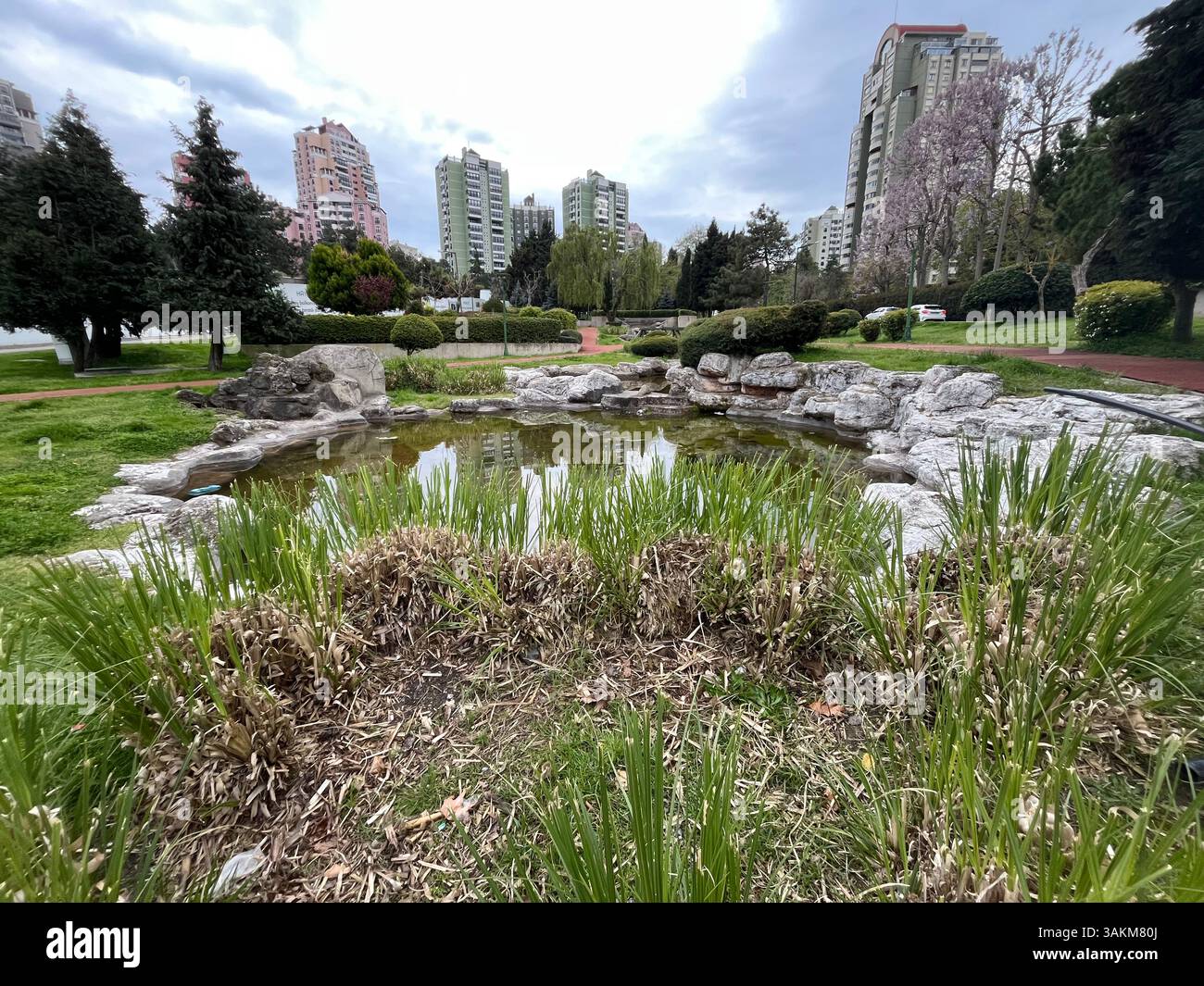 Kleiner künstlicher See und moderne Gebäude im öffentlichen Park. Stockfoto