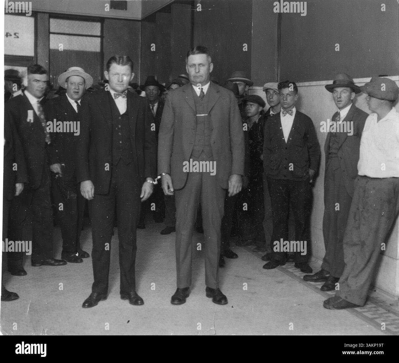 Tom Johnson, ein Mordverdächtiger, wird vor Gericht von einem Sheriff bewacht. Das Bild erfasst einen angespannten Moment während des Gerichtsverfahrens. Stockfoto