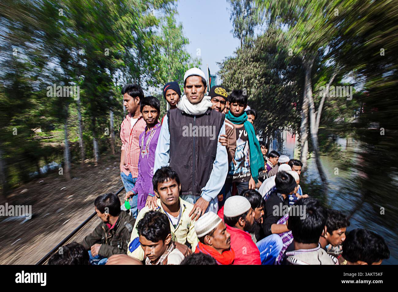 Die Passagiere fahren auf dem Dach eines rasanten Zuges in Bangladesch, was überfüllte Verkehrsmittel und Reisekämpfe während der geschäftigen Feiertage hervorhebt. Stockfoto
