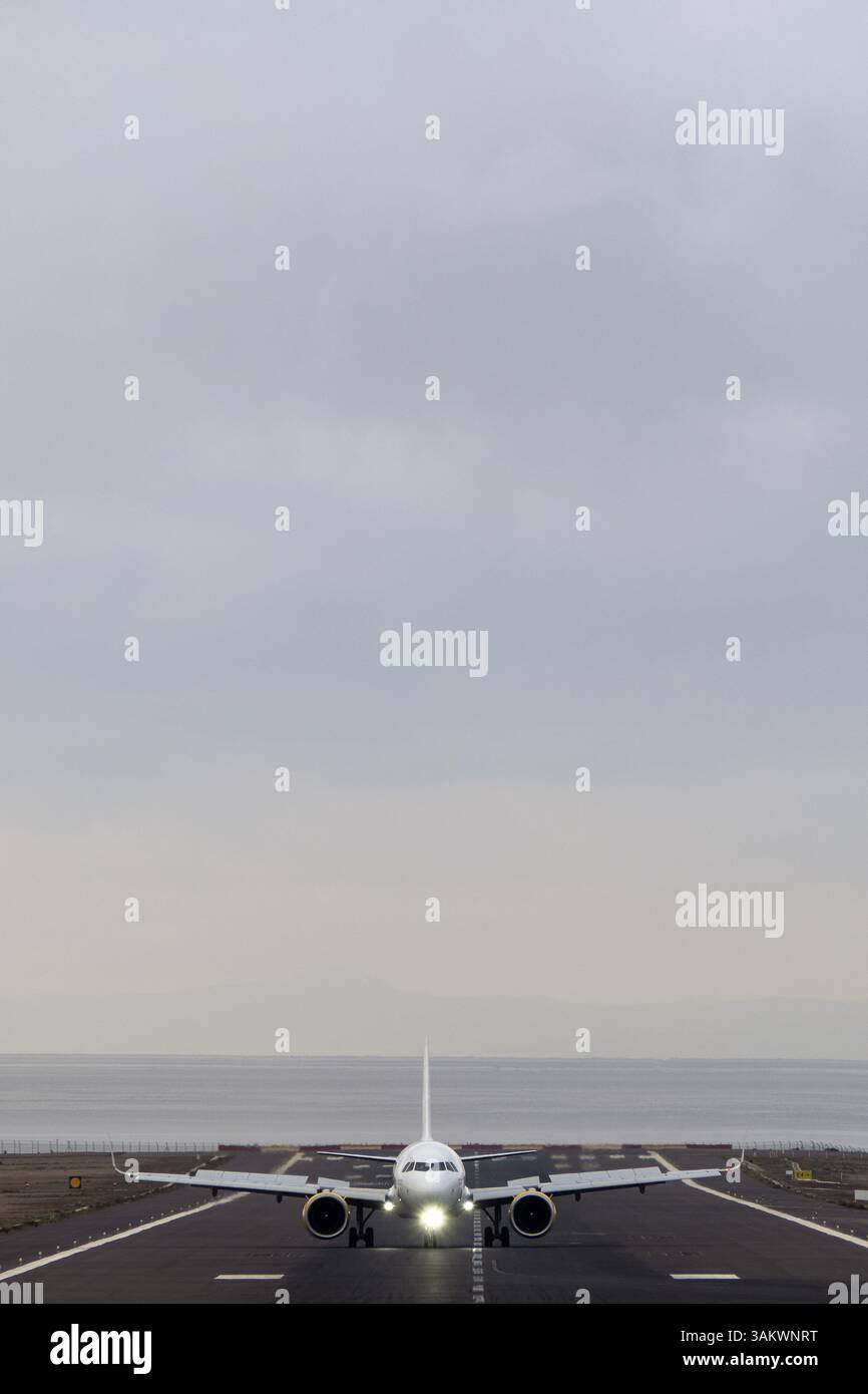 Frontale vertikale Aufnahme des Flugzeugs startet an einem nebeligen Tag vor dem Hintergrund eines grauen Himmels Stockfoto