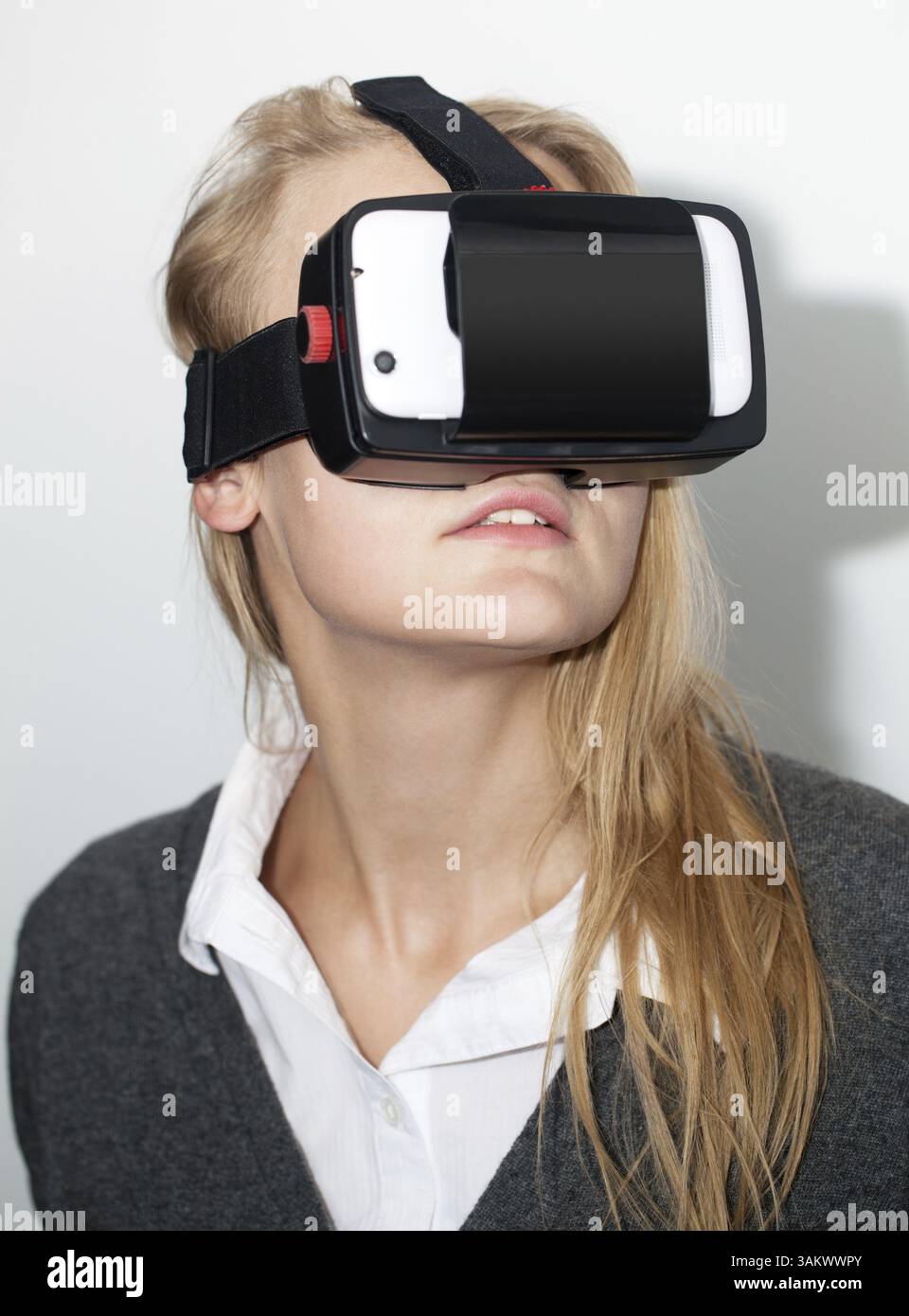 Junge blonde Frau in der erweiterten Realität, die mit Smart Phone Application virtuellen Raum erstellen Headset. Moderne unterhaltsame Technologien Stockfoto