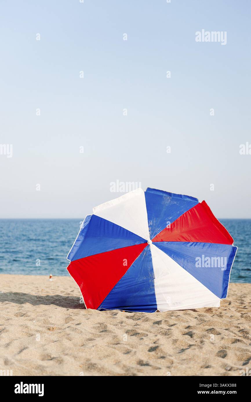 Rot weiß und blau Sonnenschirm am Strand Stockfoto