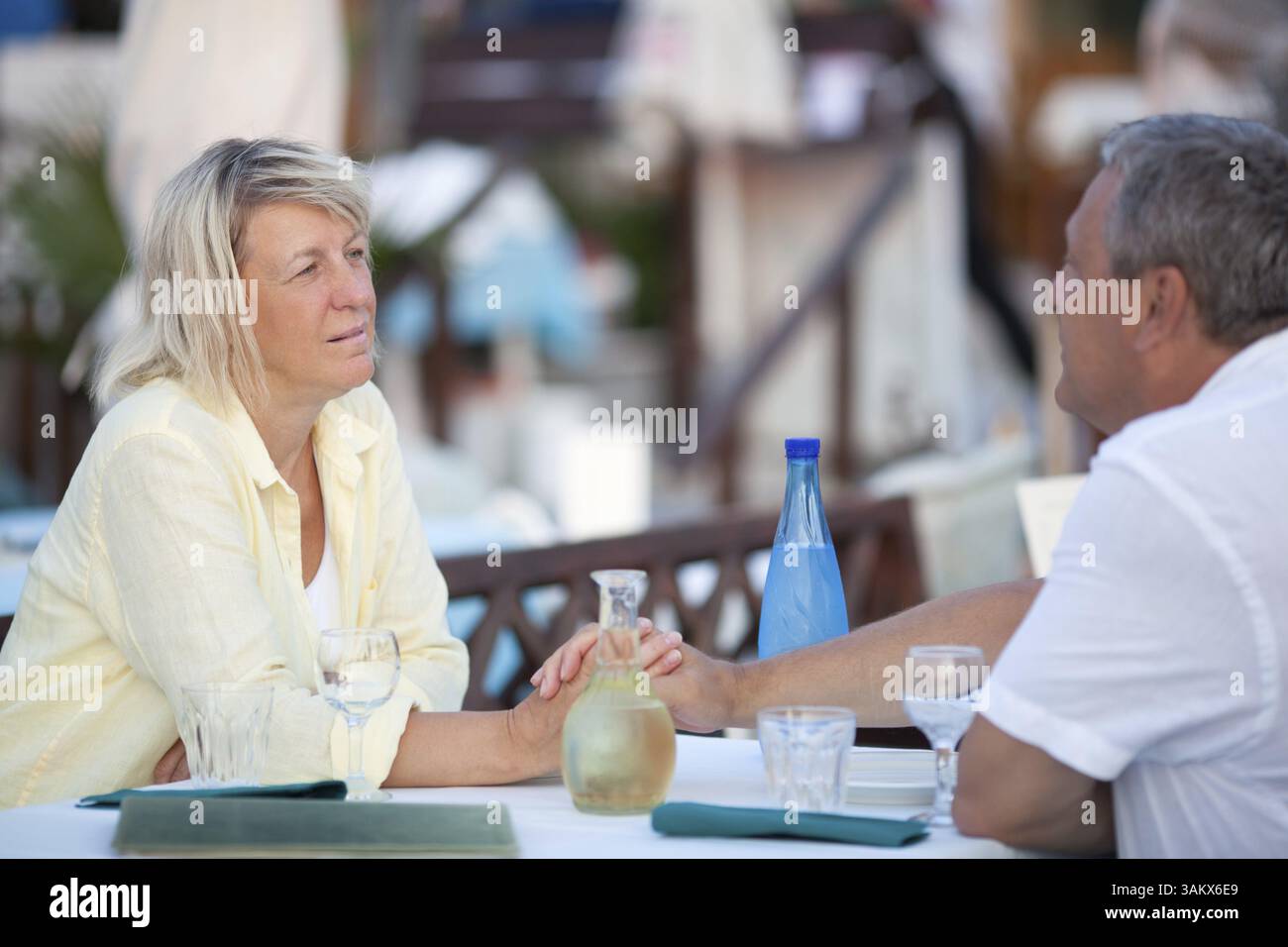 Liebevolles Paar mittleren Alters, das einen zärtlichen Moment genießt und in einem Restaurant auf eine Mahlzeit wartet und sich liebevoll in die Augen blickt Stockfoto