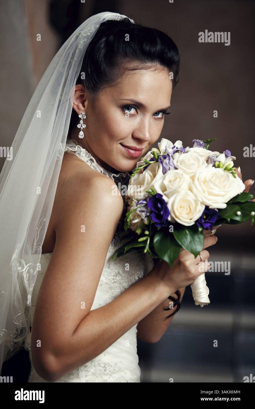 Porträt der jungen glücklichen Braut mit Blumenstrauß Stockfoto