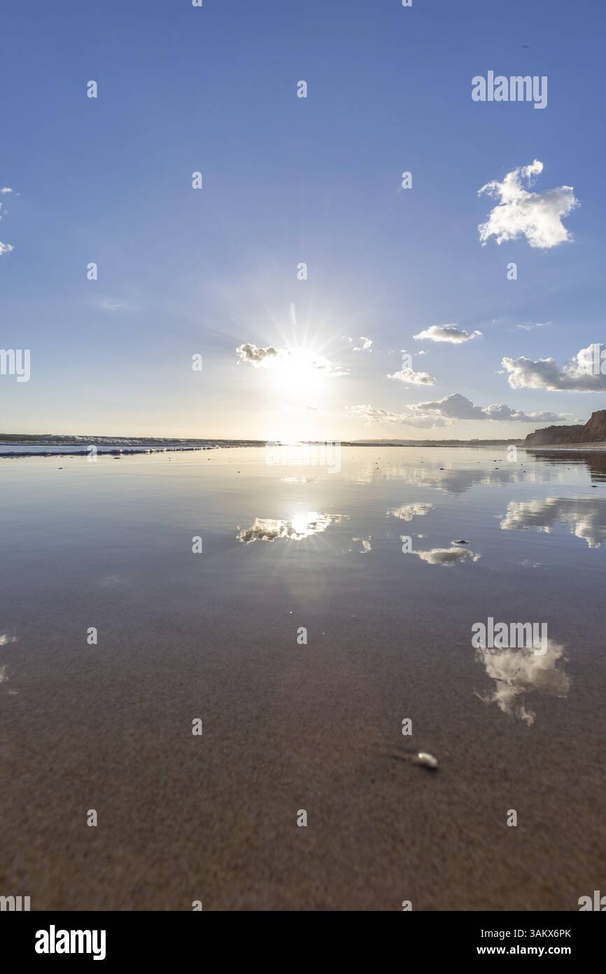 Der goldene Sandstrand von Praia da Falesia, kristallklares Meerwasser bei Ebbe mit der Reflexion des Himmels, der untergehenden Sonne und den Eigenschaften Stockfoto