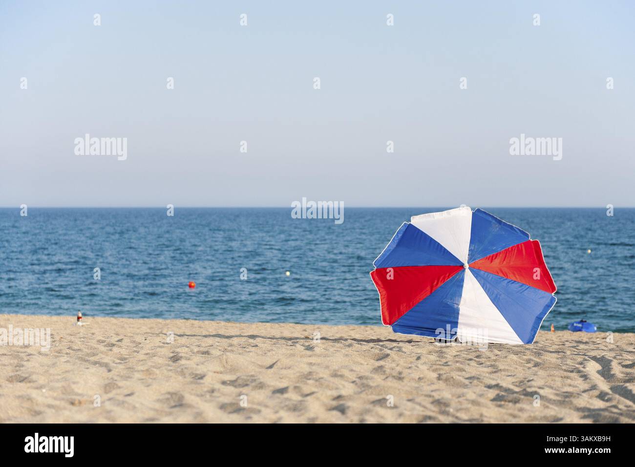 Rot weiß und blau Sonnenschirm am Strand Stockfoto