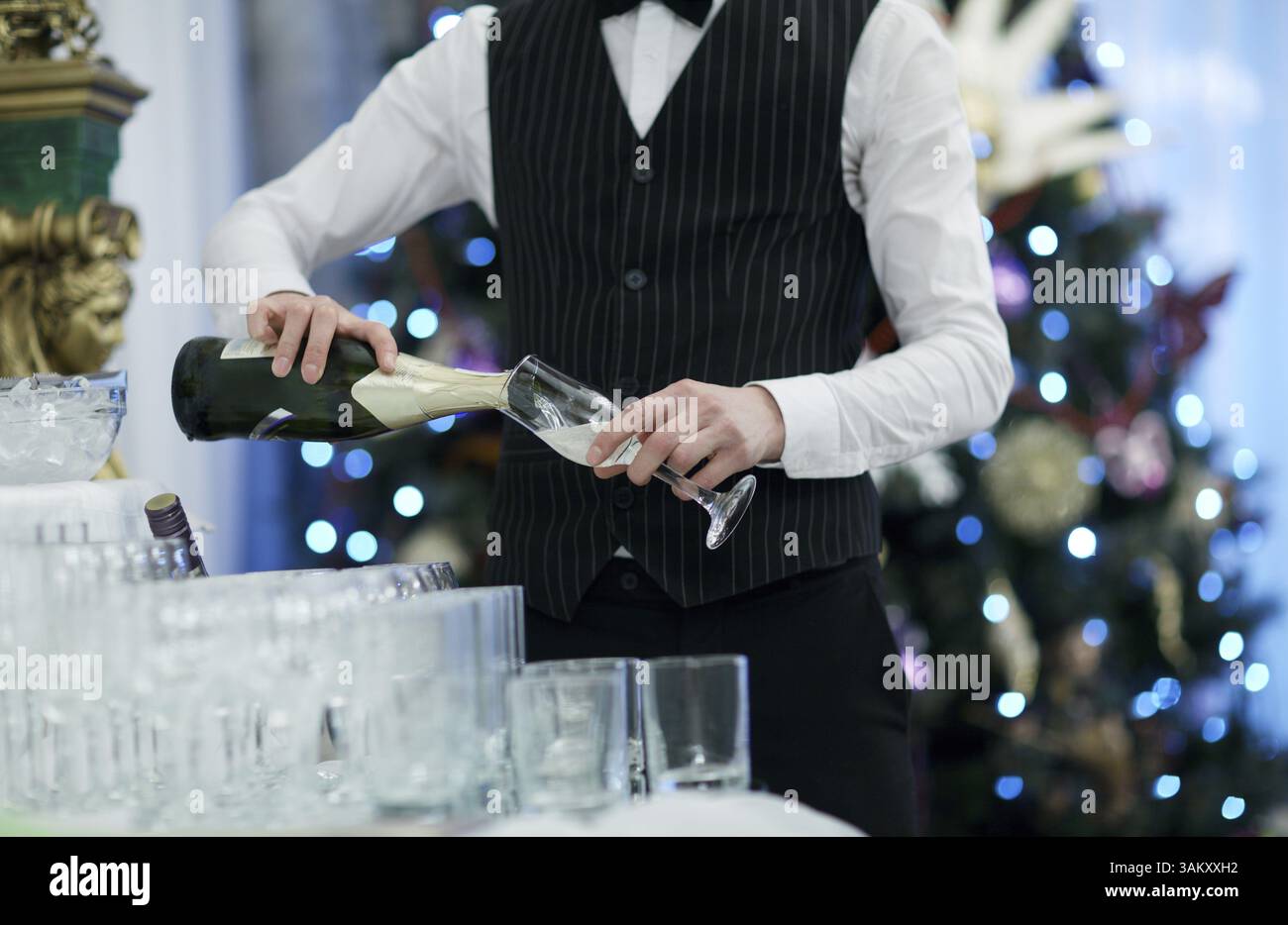 Kellner gießt Gläser Champagner auf einer Party oder festlichen Anlass mit funkelnden farbigen Lichter im Hintergrund Stockfoto