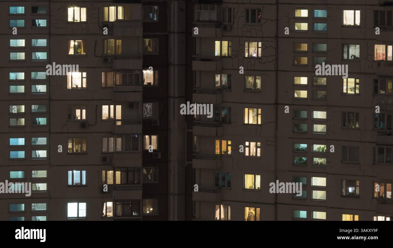 Fenster Lichter in einem mehrstöckigen Wohnhaus mit Paneelfenster bei Nacht. Altes Gebäude mit Rissen an den Wänden. Moskau, Russland, Europa Stockfoto