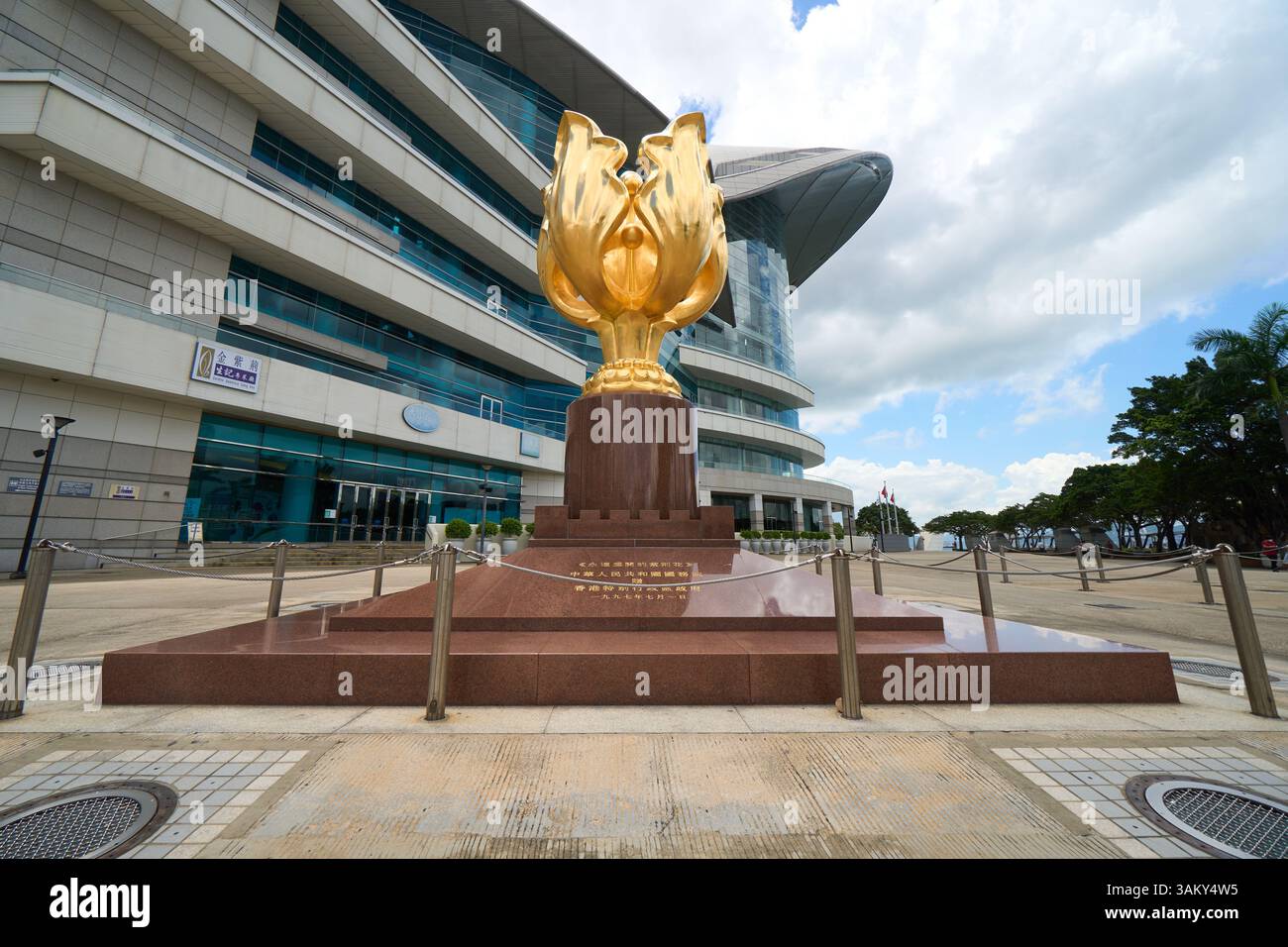 Die goldene Bauhinia-Skulptur auf dem Goldenen Bauhinia-Platz, mit HKCEC sichtbar hinter der Skulptur Stockfoto