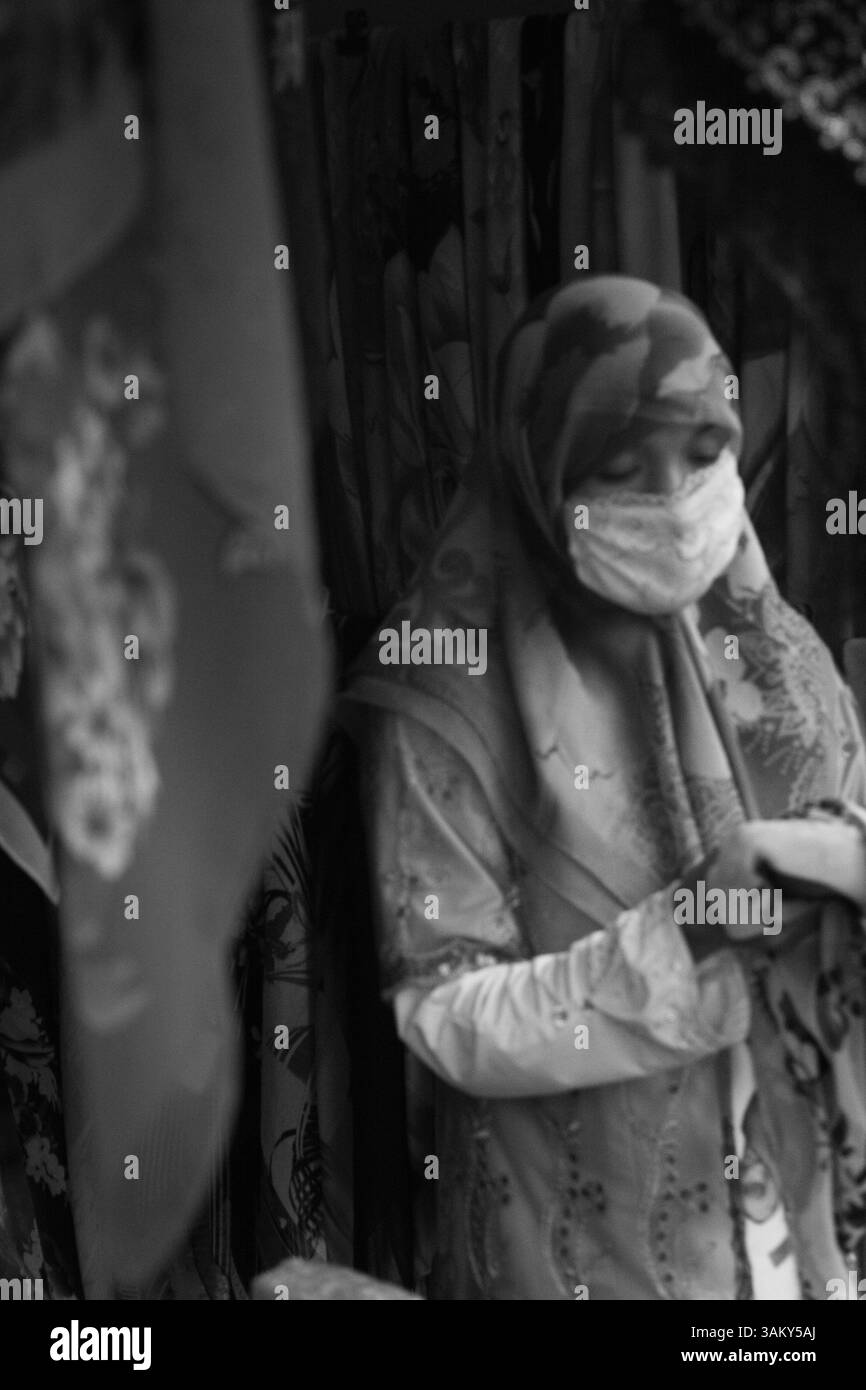 Uigurische Frau verkauft Seidenschals auf dem Markt in Korla – traditionelles Kunsthandwerk und Kulturerbe in Xinjiang, China Stockfoto