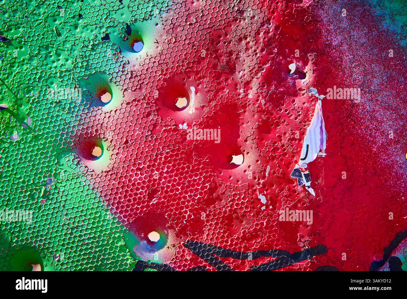 Leuchtendes Rot und Grün mit Metallstruktur aus Wabenmuster und Rundbohrungen auf Augenhöhe Stockfoto