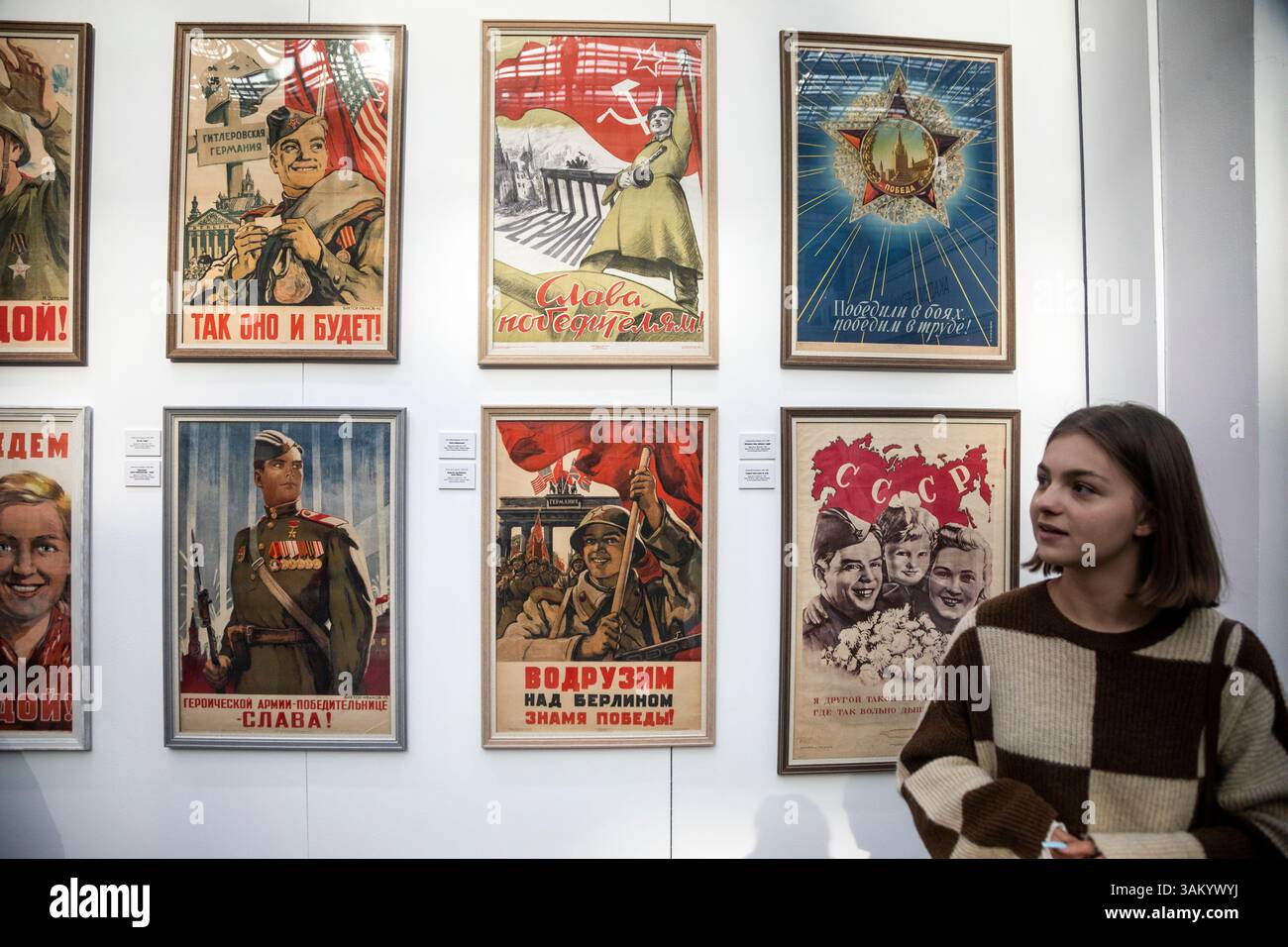 Moskau, Russland. April 2025. Ein Mädchen sieht eine Ausstellung sowjetischer Plakate aus dem Großen Vaterländischen Krieg von 1941-1945 auf der internationalen Buchmesse für hochwertige Fiktion und Sachbücher im Messezentrum Gostiny Dvor in Moskau Stockfoto