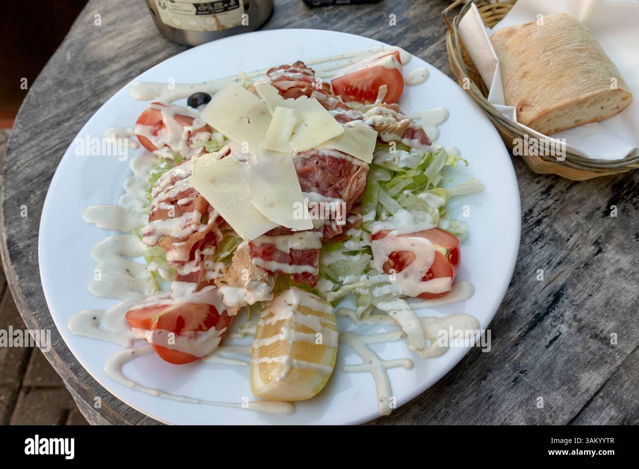 Italienischer Salat aus Hühnchen, Speck und Käse mit Mayonnaise und Beilage mit knusprigen Brötchen. Stockfoto