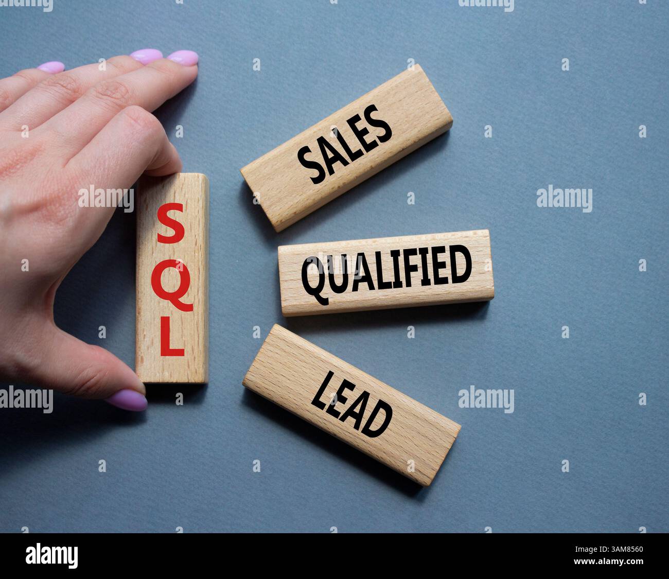SQL - qualifizierter Lead für Vertrieb. Holzwürfel mit SQL-Wörtern. Geschäftsmann Hand. Schöner grauer Hintergrund. Business- und SQL-Konzept. Kopierbereich. Stockfoto