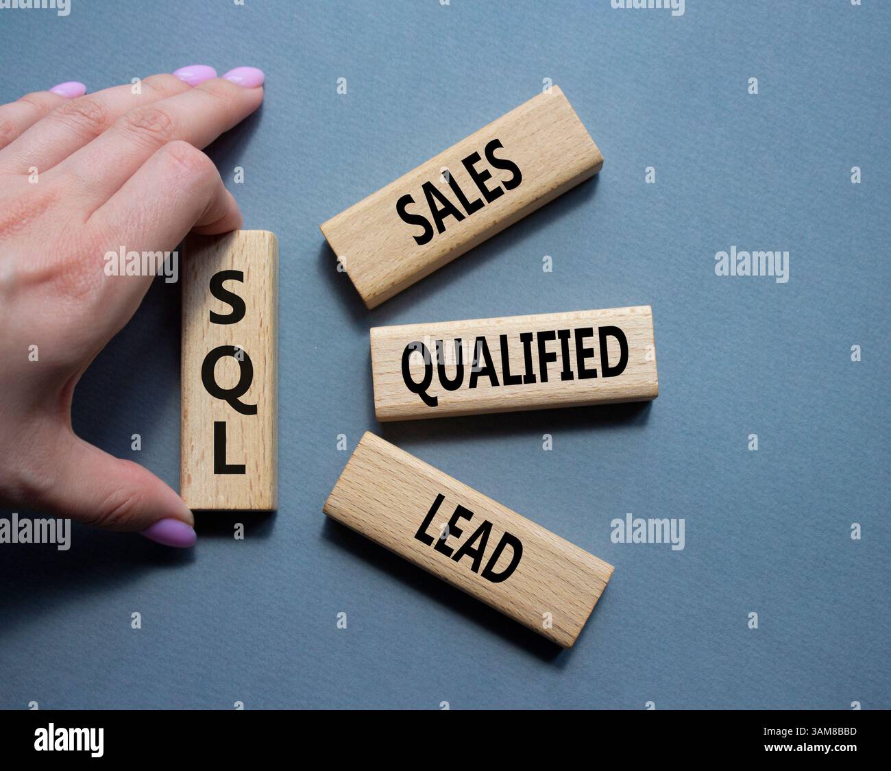 SQL - qualifizierter Lead für Vertrieb. Holzwürfel mit SQL-Wörtern. Geschäftsmann Hand. Schöner grauer Hintergrund. Business- und SQL-Konzept. Kopierbereich. Stockfoto