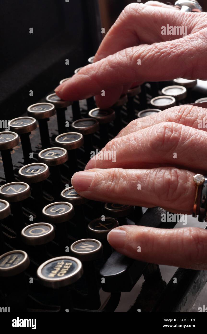 Die Hände eines älteren Menschen tippen auf eine Vintage-Schreibmaschine und fangen den Charme traditioneller Schreibweise ein. Stockfoto
