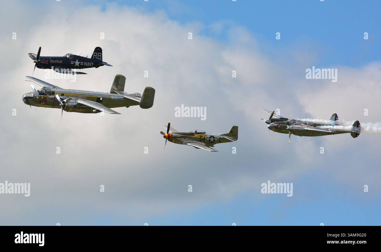 Eine Formation von vier kolbengetriebenen Warbirds, mit dem P-38-Rauch, über dem Sywell-Flugplatz, Großbritannien Stockfoto