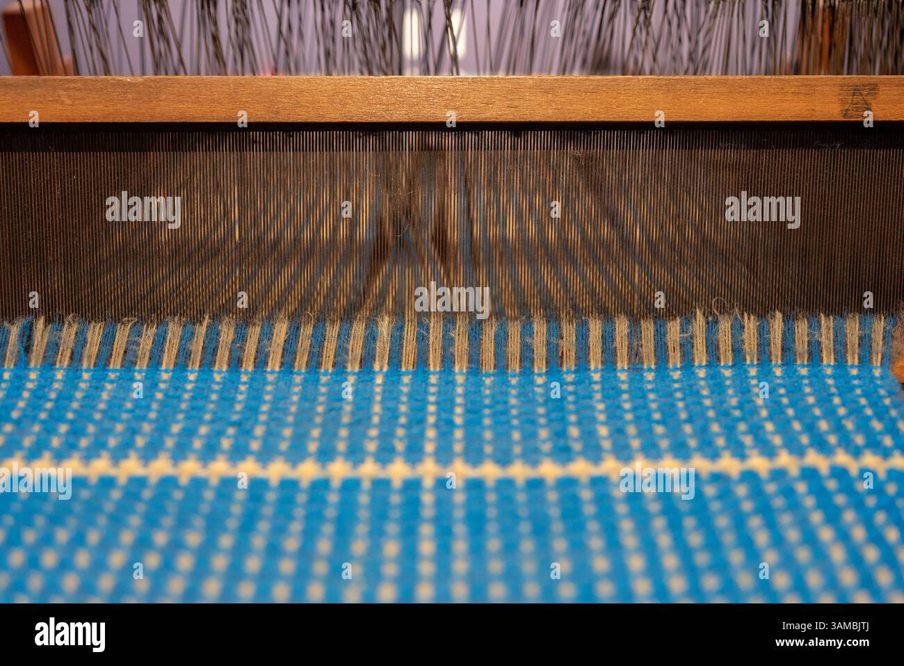 Blauer Vintage-Faden hinter einem manuellen Holzwebstuhl, alter Webstuhl. Hochwertige Fotos Stockfoto