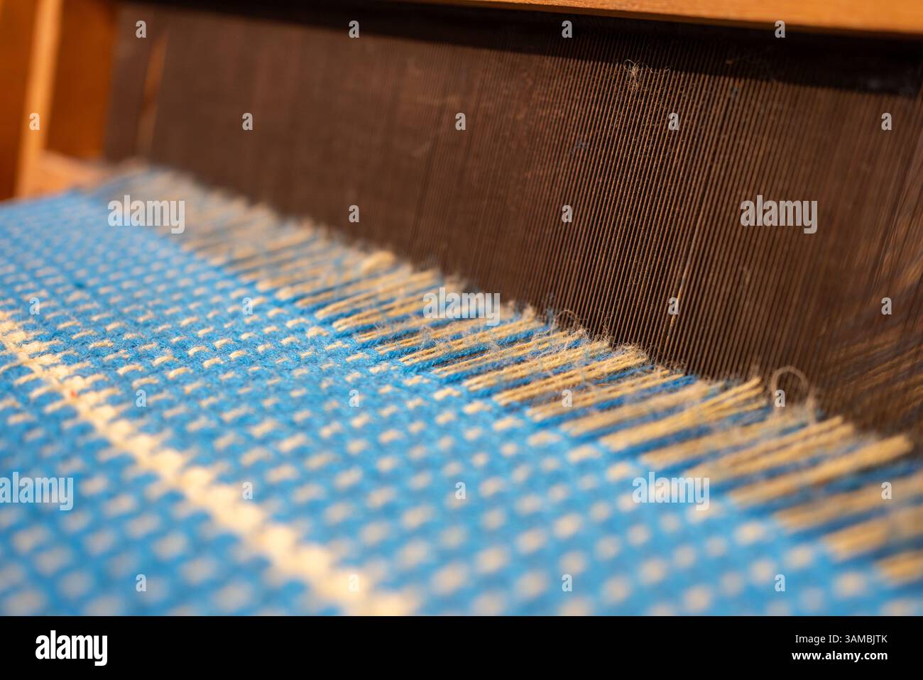 Blauer Vintage-Faden hinter einem manuellen Holzwebstuhl, alter Webstuhl. Hochwertige Fotos Stockfoto