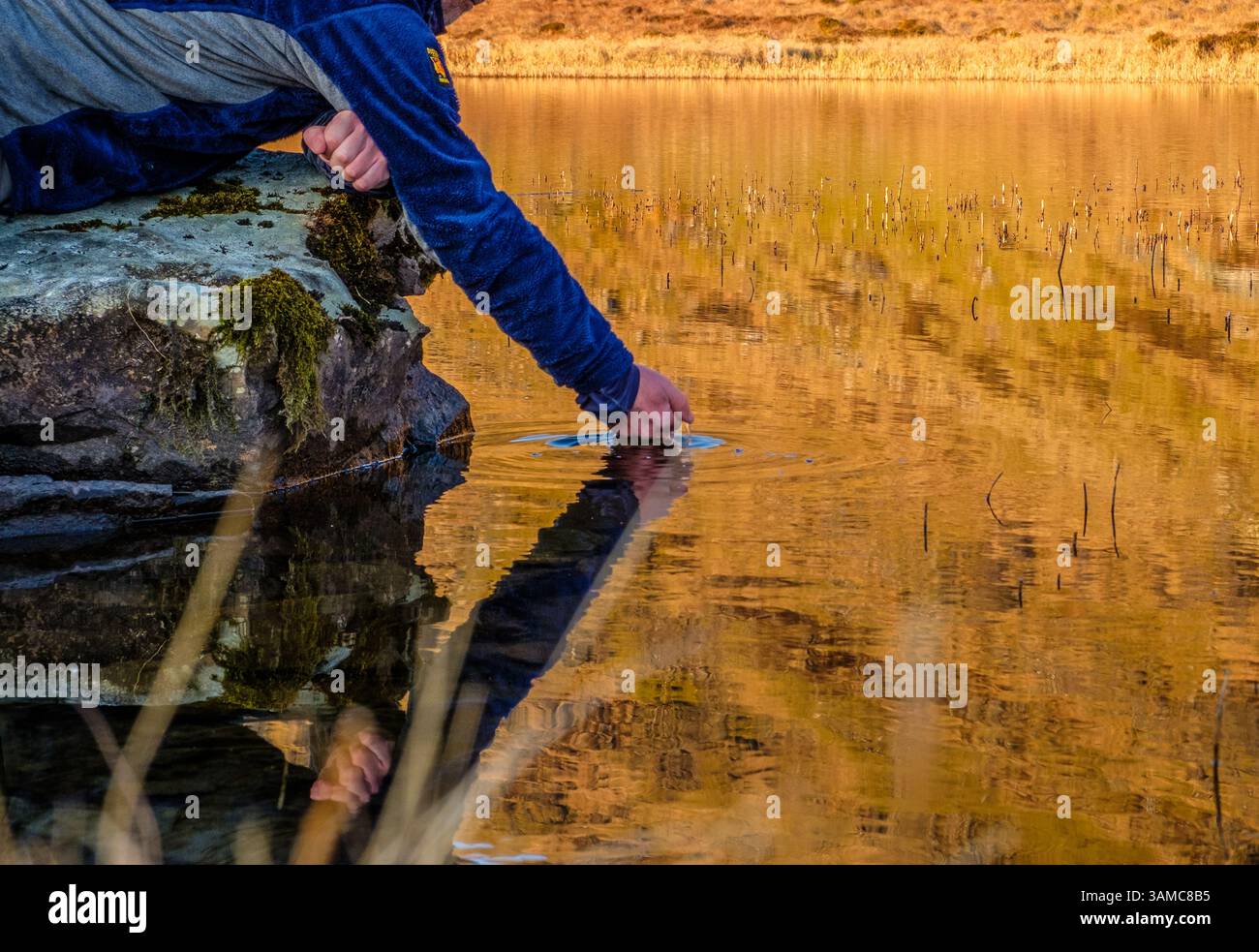 Ein Backpacker, der Wasser aus einem tarn im Lake District trinkt Stockfoto