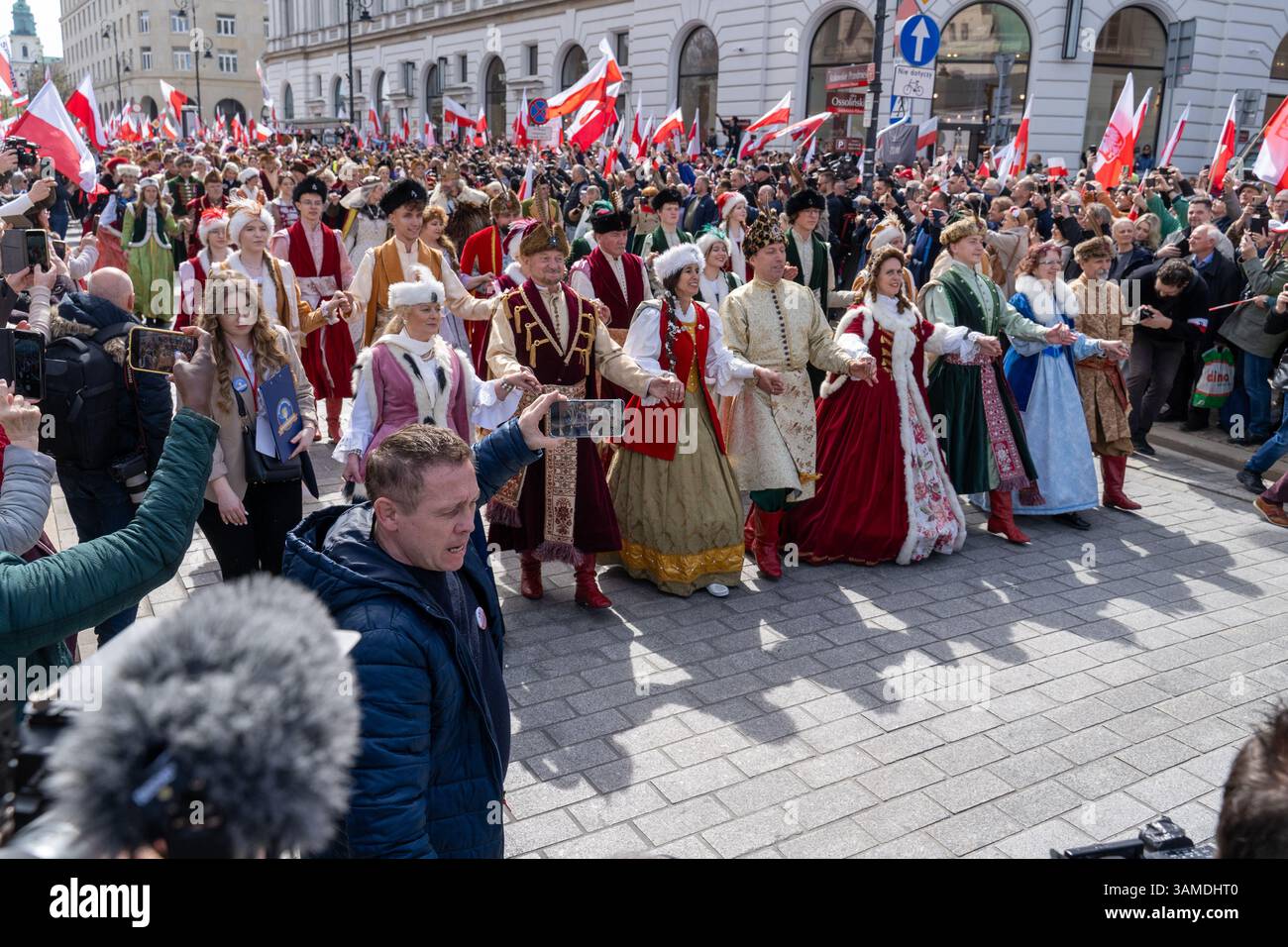 In traditioneller Tracht gekleidete Menschen führen das polonez auf, während sie am 1000. Jahrestag der ersten polnischen Königskrönung in Warschau teilnehmen. In Warschau fand ein marsch zum 1000. Jahrestag des polnischen Königreichs und zum 500. Jahrestag der preußischen Hommage statt. Tausende von Teilnehmern, viele mit weißen und roten Fahnen und Bannern, gingen durch die Straßen und skandierten Slogans wie „Republik“ und „Don't Fear Tusk“. Gegen Mittag nahm Jaroslaw Kaczynski an der Veranstaltung Teil, wie zuvor angekündigt. Um 14:00 Uhr wurde Karol Nawrocki, der Präsidentschaftskandidat, unterstützt durch das Gesetz und Stockfoto