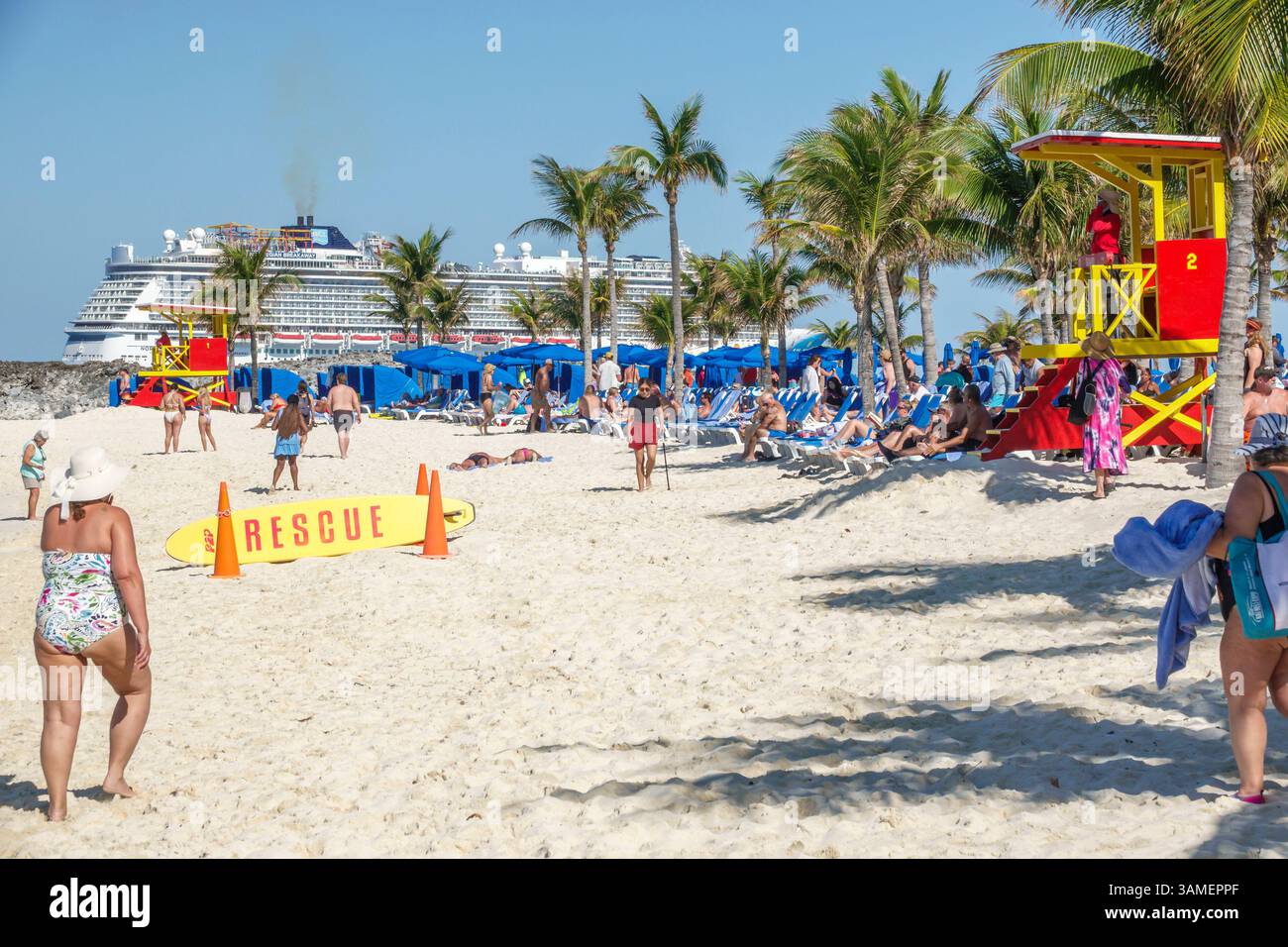 Toller Stirrup Cay die Bahamas, Kreuzfahrtstrand, entspannende Passagiere, weißer Sand, blaue Liegestühle, Rettungsschirme, Rettungstafel, Kreuzfahrtschiff vor Anker, Uferpromenade Stockfoto