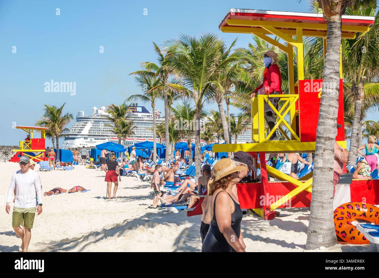 Toller Stirrup Cay die Bahamas, im Hintergrund, Passagiere sonnen sich, laufen, entspannen, weißer Sandstrand, blaue Liegen, rote gelbe Rettungsschirme, Strand um Stockfoto