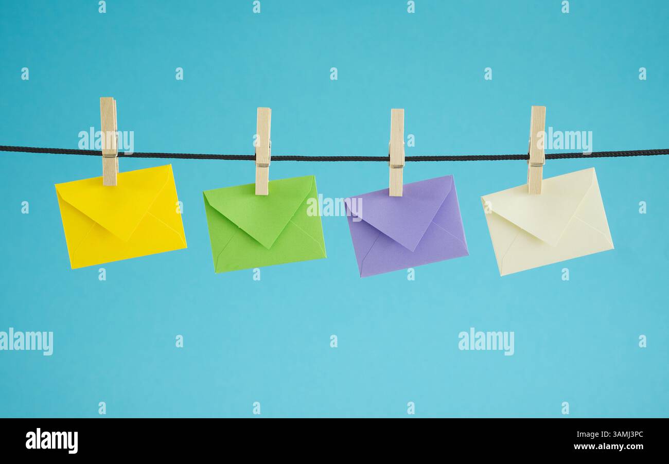 E-Mail-Marketing-Kampagnen, Website-Newsletter und Mailing-Liste Konzept mit vier aufgehängten bunten Briefumschlägen auf blauem Hintergrund. Stockfoto