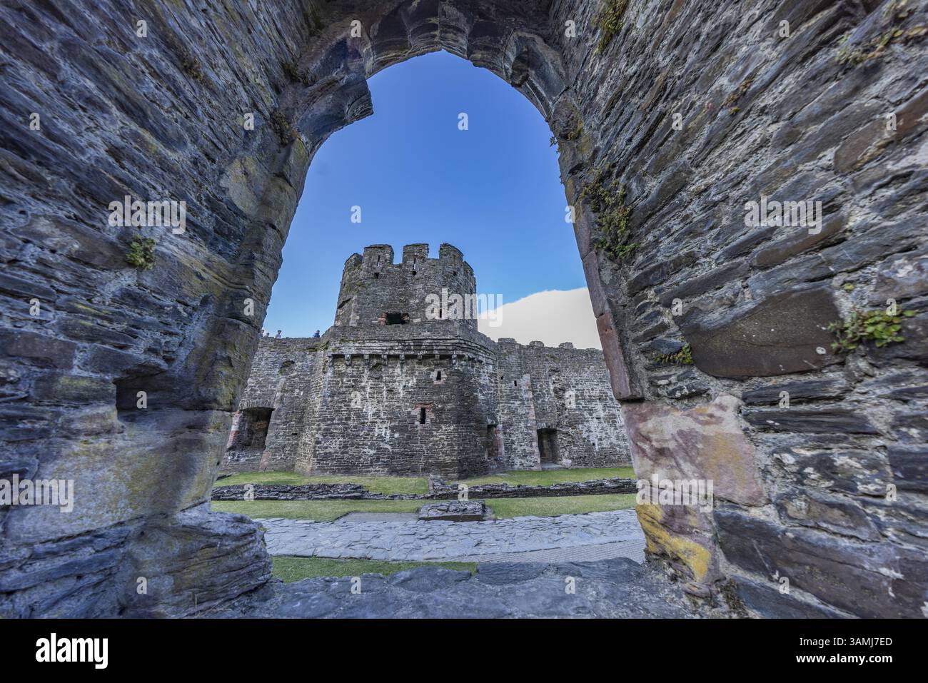 Conwy Castle, Blick durch eine bogenförmige Öffnung in der Burgmauer auf den Turm der mittelalterlichen Burg mit blauem Himmel, Conwy, Wales, Großbritannien Stockfoto
