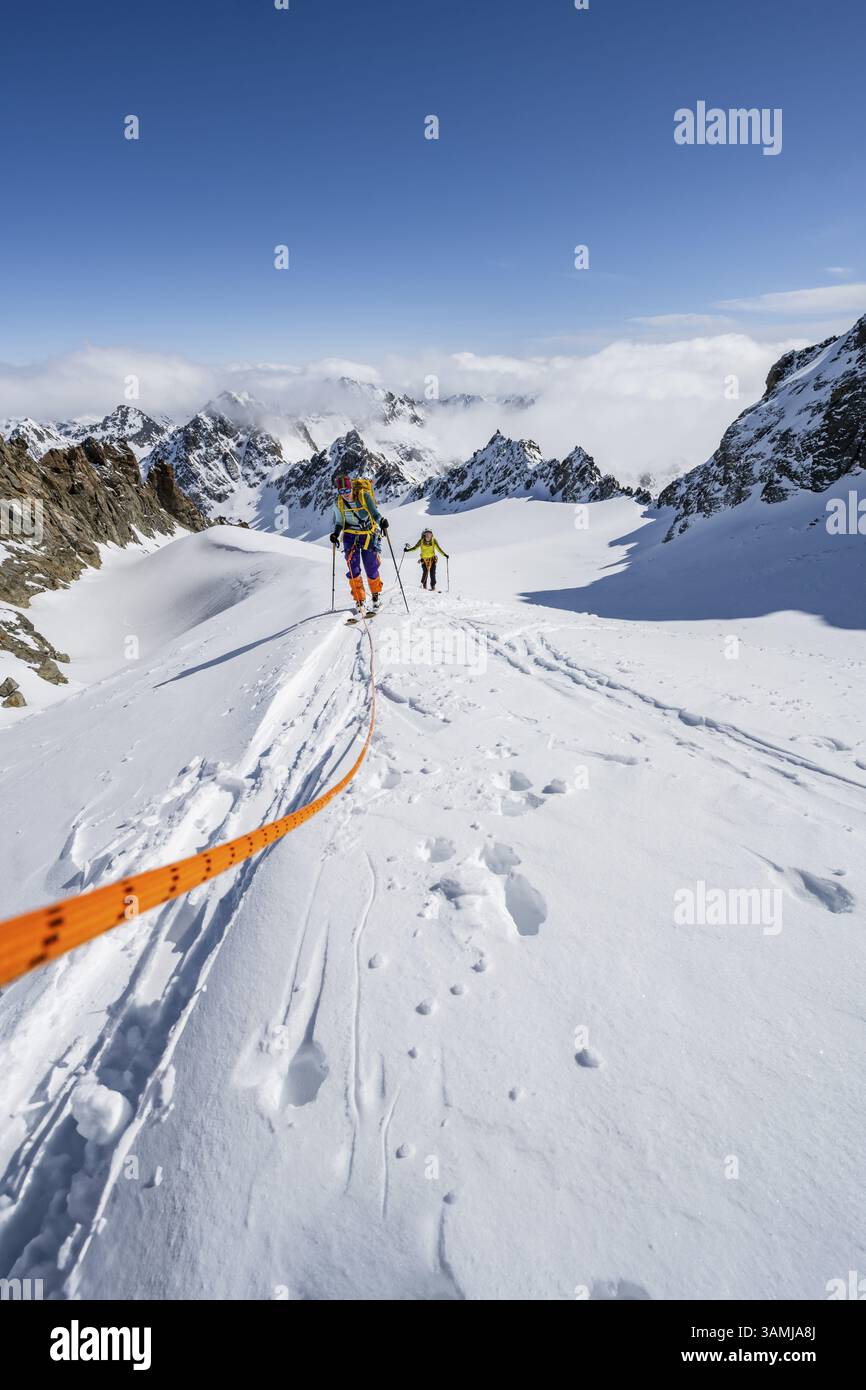 Skitourer mit Seil, Seilteam auf dem Gletscher Vadret da Porchabella beim Aufstieg zum Gipfel des Piz Kesch, Berglandschaft im Winter, alpines To Stockfoto