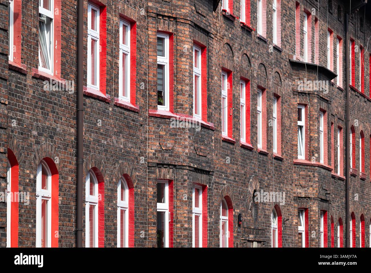 Wohnhaus aus rotem Backstein. Rote Fensterrahmen. Altershaussiedlung. Einzigartige Architektur. Kattowitz Nikiszowiec. Polen Stockfoto