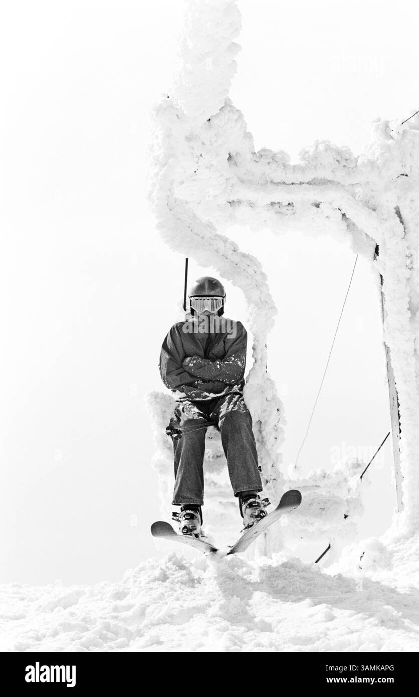 Ein junger Mann sitzt auf einem gefrorenen Sessellift in Jahorina, Bosnien. Stockfoto